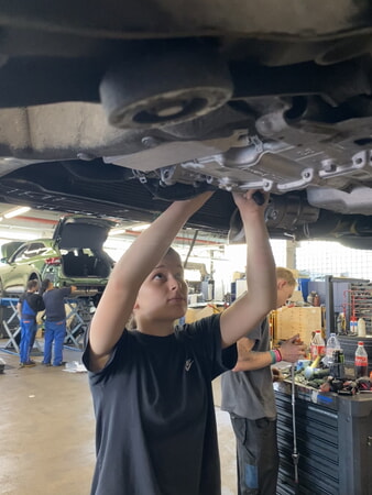 Bildunterschrift 3: Damit die 15-jährige Carla auch an die untenliegenden Schrauben drankommt, wird das Auto mit der Hebebühne angehoben. (Foto: Handwerkskammer Region Stuttgart)