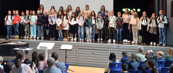 Foto (EG): Die Klasse 5T mit ihren Lehrkr&auml;ften bei der Begr&uuml;&szlig;ung in der Aula